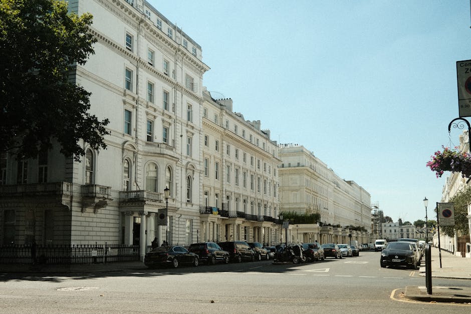 Photograph of a historic multi-story building with ornate architectural details, cream-colored facades, decorative window trims, and classical cornices, illuminated by natural daylight against a clear